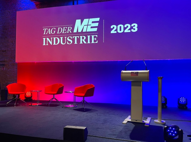 Leere Bühne mit einem Podium und drei Stühlen für Panel beim Tag der M+E-Industrie 2023 in Berlin
